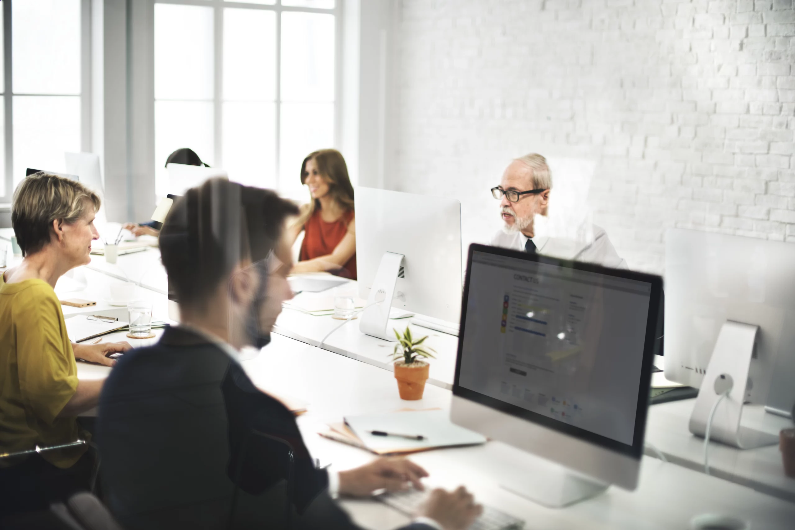 Une équipe professionnelle en réunion, utilisant des ordinateurs pour planifier des campagnes digitales, avec des bureaux modernes en arrière-plan.